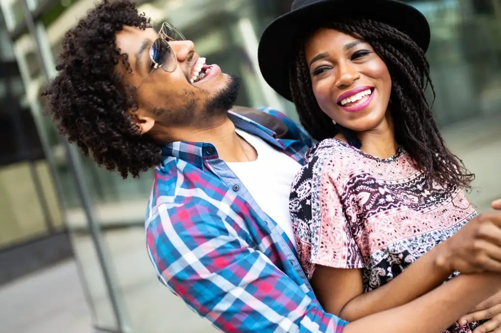 Happy young black couple hugging and laughing outdoors