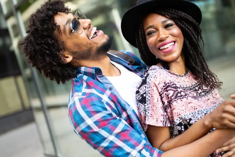 Happy young black couple hugging and laughing outdoors